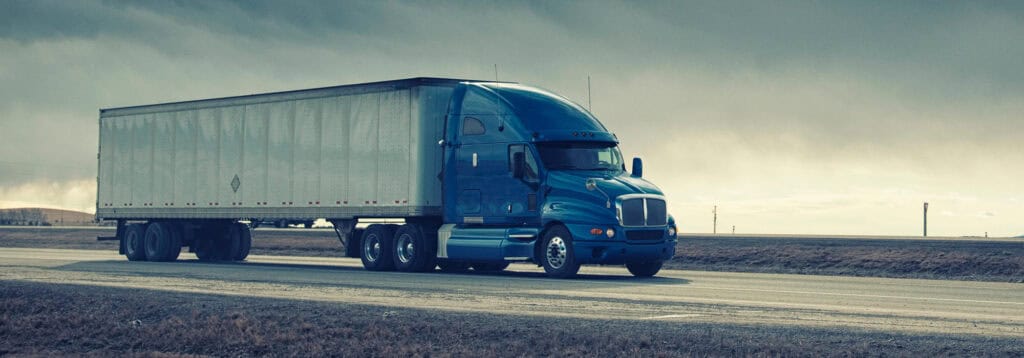 tractor trailer driving quickly down empty highway