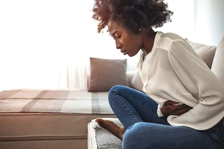 woman-holding-stomach-in-pain-sitting-on-couch-paragard-iud