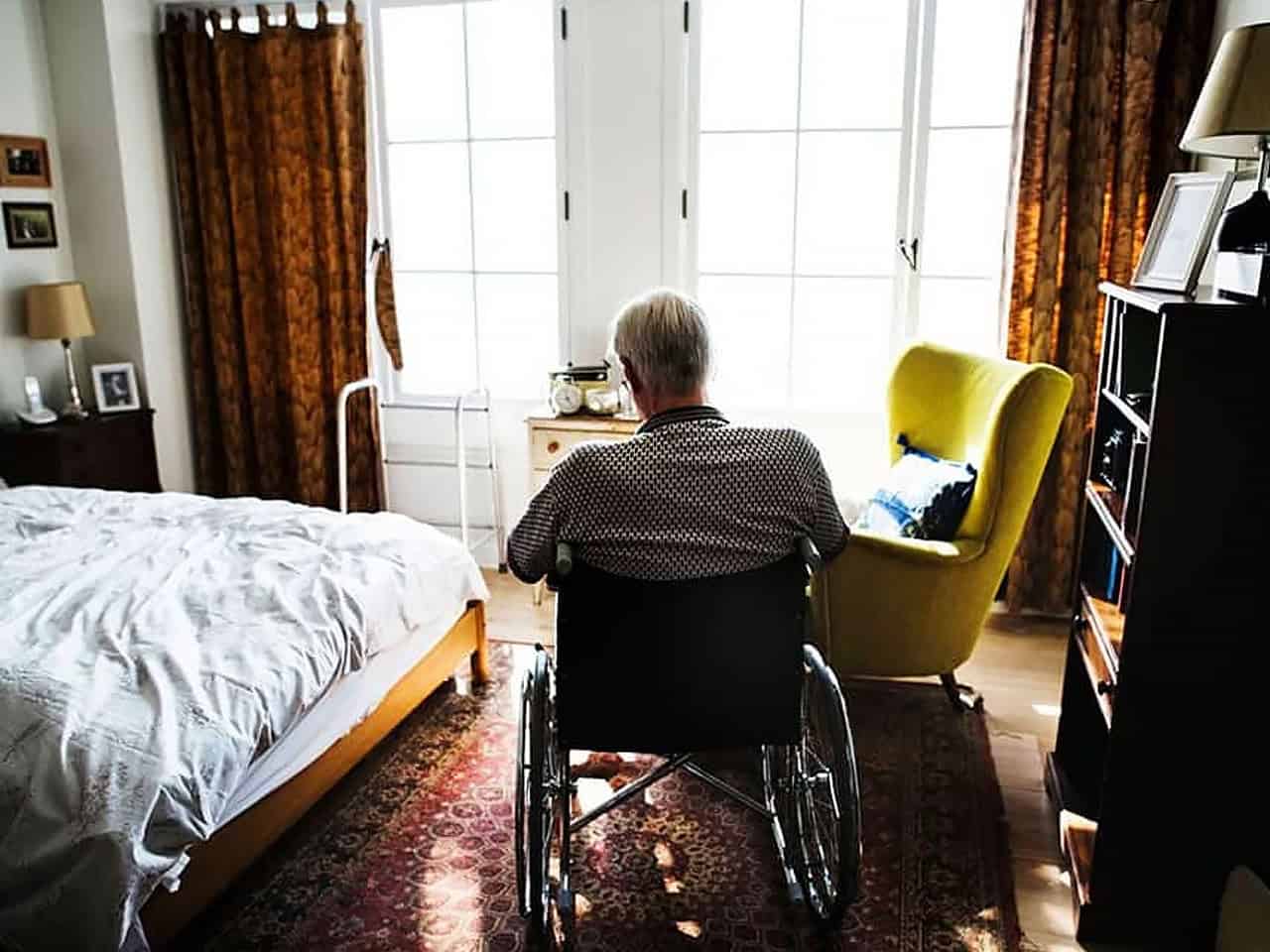 Elderly man in wheelchair looking out window