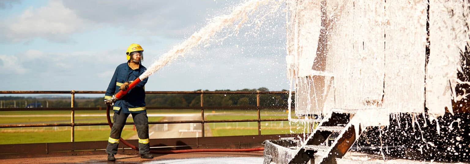 Fireman spraying foam on a wall 1536x538