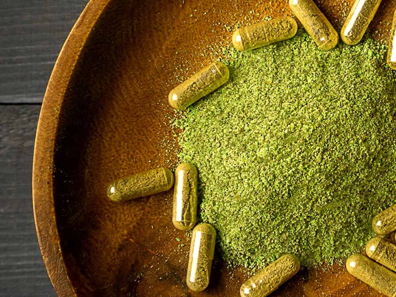 Kratom capsules in wooden bowl