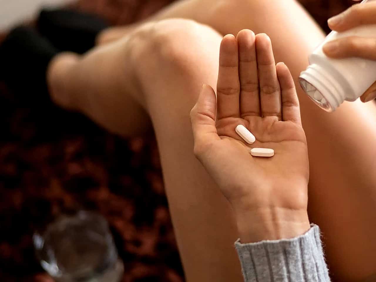 Woman holding bottle and two pills