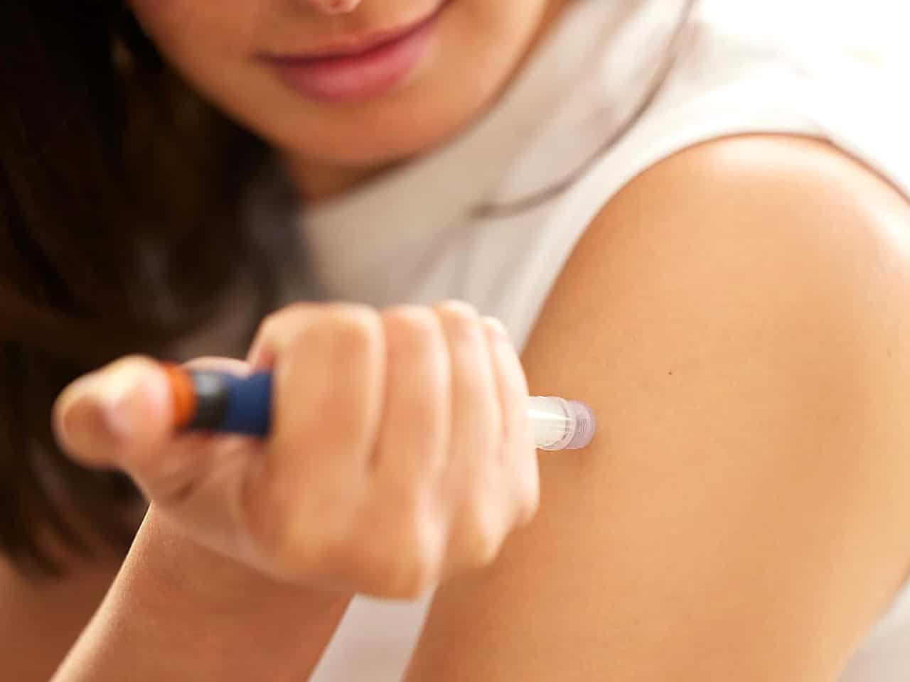 Younger woman injecting medication into arm