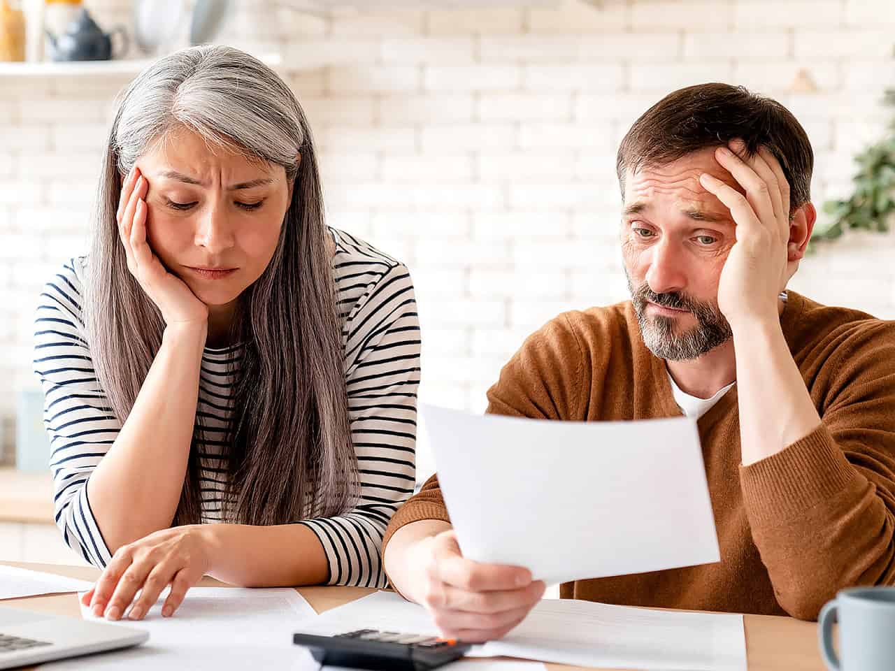 Married couple at kitchen table reviewing bills