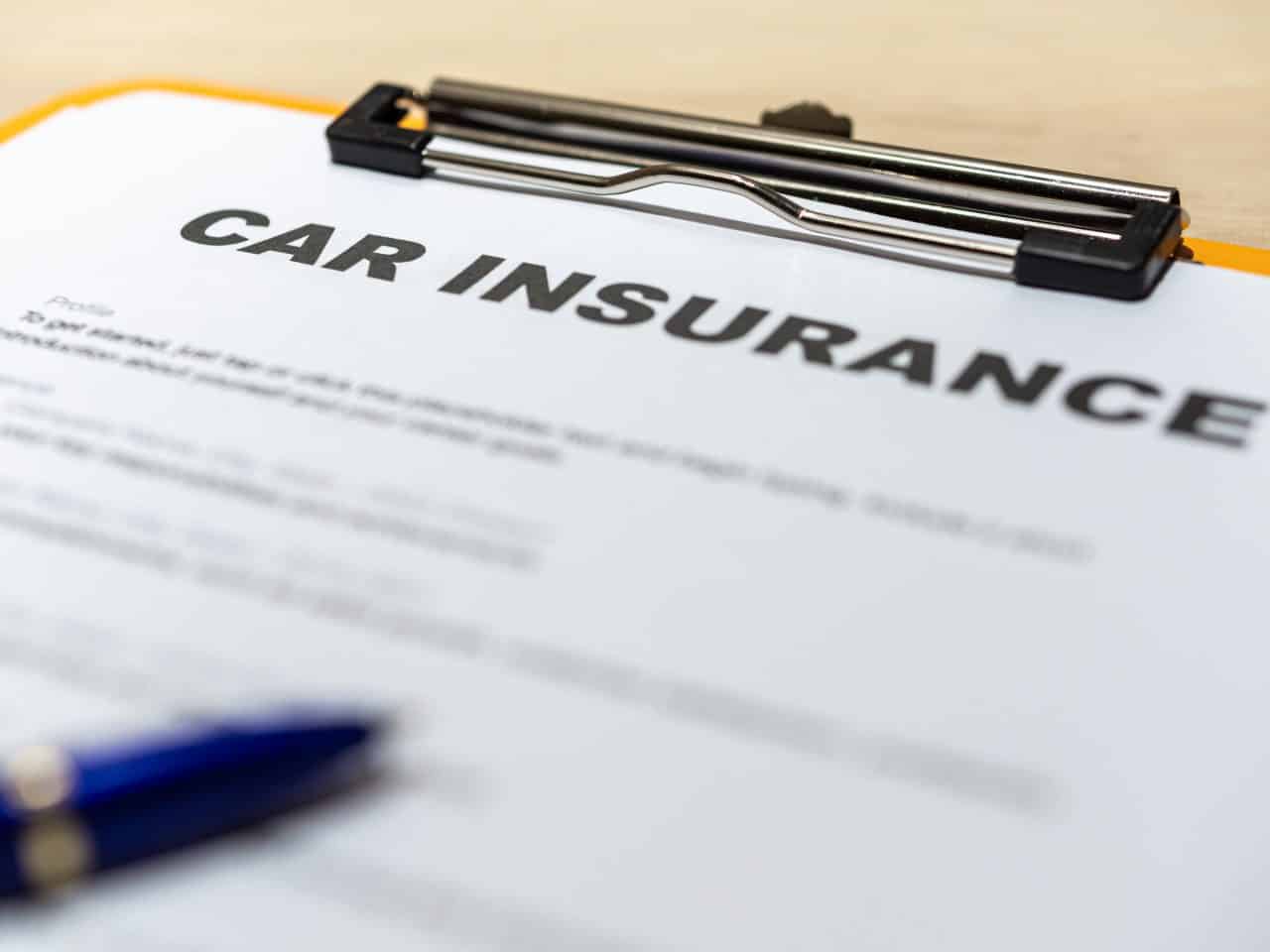 Car insurance form on clipboard pen desk